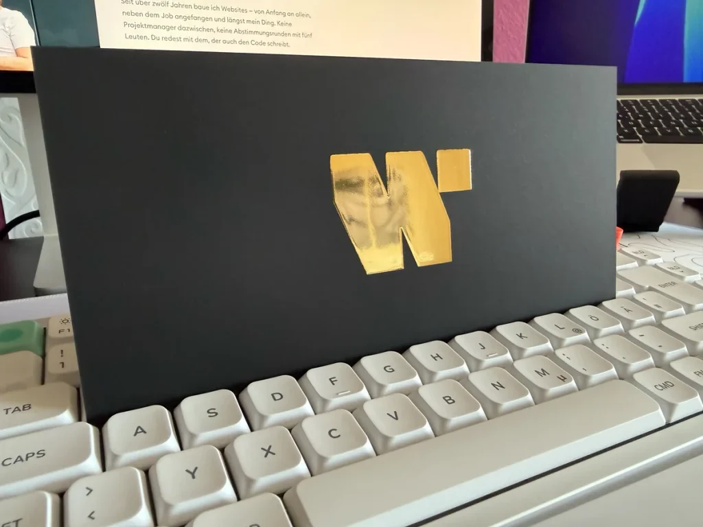 Begleitkarte des German Web Awards 2026 mit goldgeprägtem Logo des Ausrichters